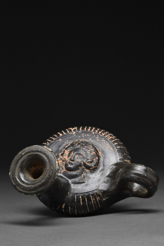 ANCIENT GREEK GLAZED GUTTOS WITH GORGONEION HEAD
Ca. 360-320 BC. A ceramic blac...