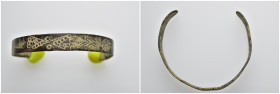 A copper-alloy open-ended bracelet decorated with wavy lines and dots, and with stylized leaf terminals. 51mm, 8.69 gr.