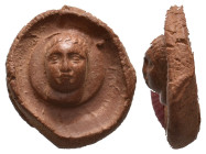 Graeco-Roman clay seal impression (C. 200 AD.)
Obv: Laureate and nimbate facing head, probably of Helios?
Rev: Blank.

Cf. Roma Numismatics 12, 13...
