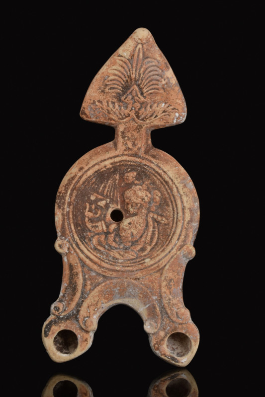 ROMAN TERRACOTTA TWO-SPOUTED OIL LAMP WITH APOLLO KITHAIROIDOS
Ca. 100-200 AD. ...