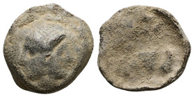 PB Roman provincial lead tessera (AD 1st-3rd centuries) 
Obv: Janiform female heads, with central earring.
Rev: Illegible Greek legend in two lines: C...