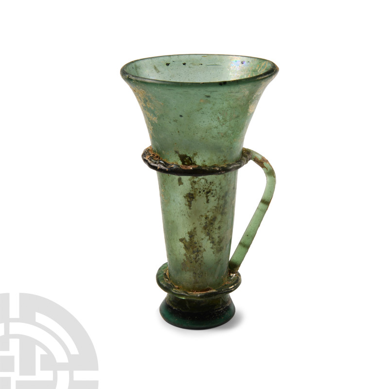 Late Roman Green Glass Vessel with Handle
Circa 4th century A.D. Featuring a cy...