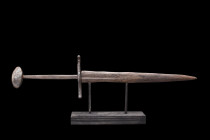 MEDIEVAL IRON DAGGER WITH DISC-SHAPED POMMEL

 Ca. 1300-1500 AD
 A short iron double-edged dagger with a slightly curved sculptured cross guard wit...