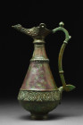 SELJUK BRONZE EWER WITH LAMP-SHAPED SPOUT

 Ca. 1100-1200 AD
 A bronze ewer with inverted piriform body, resting on a low foot, is adorned with a m...