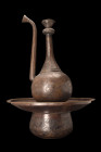 QAJAR BRASS EWER AND BASIN - AFTABEH

 Ca. 19th century AD
 A brass ewer and basin set including a slender ewer that rises from a concave splayed f...