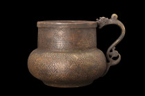 TIMURID DRAGON HANDLED EWER

 Ca. 15th century AD
 A brass ewer featuring a magnificent dragon handle, with its S-shaped body, trefoil-shaped tail,...