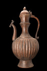 INDIAN EWER WITH TWO SPOUTS

 Deccan, ca. 16th-18th century AD
 A ewer with a melon-shaped body and elegant vertical grooves, the ewer stands atop ...