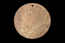 ISLAMIC BRASS DISC WITH CALLIGRAPHY

 Ca. 17th-19th century AD
 A brass circular disc adorned with intricate Arabic inscriptions. The disc is pierc...
