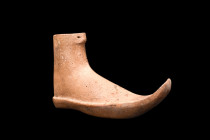 PHRYGIAN BOOT-FORM RHYTON 

 Western Anatolia, ca. 800-700 BC
 A tan pottery low boot having pointed toe curved off to the side and an incise-stitc...
