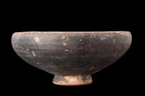 APULIAN BLACK GLAZE FOOTED BOWL

 Ca. 400-300 BC
 A terracotta dish featuring a hemispherical bowl and a concave foot, characteristic of ancient Gr...