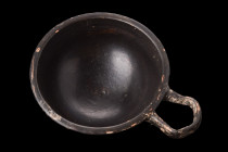 APULIAN BLACK GLAZE CUP WITH HANDLE

 Ca. 400-300 BC
 A black glazed cup featuring a round, deep body on a flared foot, with a looped handle that h...