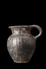 APULIAN BLACK GLAZE CUP WITH HANDLE

 Ca. 400-300 BC
 A black glazed mug featuring an elegant inverted pear-shaped body with incised vertical groov...