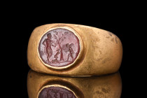 ROMAN GOLD RING WITH INTAGLIO SCENE - CUPID, GOAT AND HERCULES

 Ca. 100-300 AD
 A finely engraved intaglio set in a gold ring with widening should...
