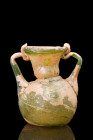 ROMAN GLASS VESSEL WITH HANDLES

 Ca. 300-400 AD
 A pale green glass jar with a rounded rim, a funnel-shaped neck, and a squat lower body with a co...
