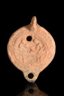 ROMAN TERRACOTTA OIL LAMP WITH EROTIC SCENE

 Ca. 200-300 AD
 A terracotta oil lamp of a discoid body, looped handle, small nozzle, rounded spout, ...