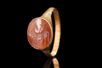 ROMAN GOLD RING WITH HORSE AND LEGIONARY STANDARD 

 Ca. 100-300 AD
 A skillfully engraved carnelian intaglio boasting an impressive depiction of a...