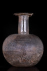 LARGE ROMAN GLASS FLASK

 Ca. 100-200 AD
 A large heavy blown glass flask with a globular body, long tubular neck, and flat base, with wheel cut ba...
