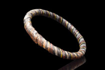 LATE ROMAN GLASS BRACELET

 Eastern Mediterranean, ca. 400-500 AD
 A glass bracelet comprised of black, white, red, and yellow thin rods fused toge...