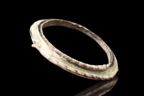 LATE ROMAN GLASS BRACELET

 Eastern Mediterranean, ca. 400-500 AD
 A large glass bracelet having a solid center band in yellow, trimmed on both edg...