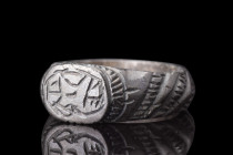 ROMAN BRONZE RING WITH STYLISED PATTERN 

 Ca. 200-500 AD
 A bronze ring with a circular loop with diagonal, incised decoration on the outside, and...