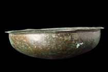 ROMAN BRONZE LARGE BOWL

 Ca. 200 AD
 A bronze bowl of wide and deep body, with a rounded bottom and an everted lip that lends it a commanding pres...