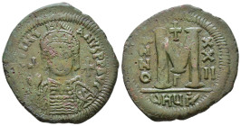 Justinian I. 527-565 AD. Follis. D N IVSTINIANVS P P AVG, helmeted, draped and cuirassed bust facing, holding globus cruciger and shield; cross in rig...