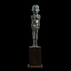 * STATUETTE FÉMININE
En alliage cuivreux à patine verte, représentée debout en position frontale. La position des jambes et des bras serrés près du c...