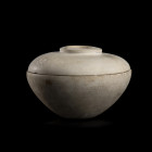 VASE AVEC COUVERCLE 
En albâtre calcifié. À panse biconique et lèvre plate. Le couvercle (non pertinent) quant à lui est pourvu d'une ouverture circu...