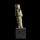 CHAOUABTI FÉMININ
En faïence à glaçure verte et noire. Figuré dans sa gaine mommiforme; perruque tripartite. Les mains jointes sous la poitrine, tien...