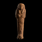 RARE CHAOUABTI D'ANKH FENMOUT
En terre-cuite. Figuré dans sa gaine mommiforme, les mains croisées, il tient les houes. Il porte la perruque tripartit...