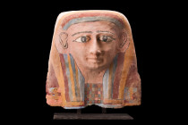 EGYPTIAN FACE FROM A WOODEN COFFIN LID

 26th Dynasty, ca. 664-525 BC
 The face lid features a striking yellow-blue striped tripartite wig, symboli...