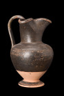 GREEK BLACK-GLAZE OINOCHOE

 Ca. 400-300 BC
 A pottery oinochoe characterized by its black-glazed surface and distinctive shape. It features an inv...