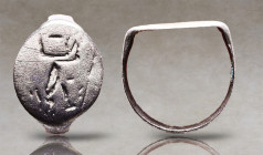 Greek Silver Ring with Seated Goddess, 5th-3rd century B.C. A silver ring composed of a D-section hoop and large discoid bezel, engraved with a goddes...
