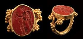 A roman red jasper intaglio, mounted in an ancient gold ring. Victory. The winged and draped figure is standing up, turned to the left, holding a laur...