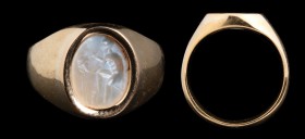 A roman chalcedony intaglio, mounted on a modern gold ring. Manufacturer. The old, bearded man is modelling/chiselling a head with a tool; the head is...