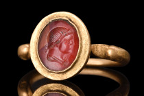 Ca. 300 AD.
A gold finger ring with its band formed into a hoop with duck-head finials, which adds a unique touch to the design. The bezel cell is set...