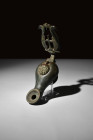 Ca. 4th-6th century AD.
An oil lamp meticulously crafted from bronze, boasts a pear-shaped, hollow body that seamlessly converges into a short nozzle ...