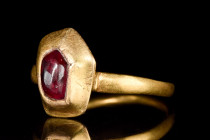 Ca. 1400 AD.
A gold ring with a slender round hoop, slightly widening to a plano-convex bezel with inset ruby cabochon. 
Size: D: 19.51mm / US: 9 5/8 ...