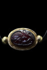 Ca. 200 AD.
A cabochon garnet engraved with a scene of Leda and the Swan set in a gold pendant setting flanked by two spheres on each side. Leda, a pr...