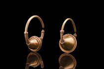 Ca. 500-600 AD.
A matching pair of electrum earrings, crafted with utmost skill and care. Each earring features a round-section hoop with a central, b...