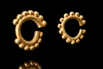 1st millenium BC.
A matched pair of gold earrings. At the heart of each earring is a round hoop, expertly crafted from the finest gold. The gold has a...