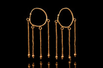 Ca. 600 AD.
A pair of gold earrings formed of a round hoop embellished with a sphere and four loops suspended below. From each loop hangs a short gold...