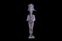 Late Period, 26th Dynasty, Ca. 664-525 BC.
A silver votive figurine of Osiris wearing an atef crown, plumed on each side with ostrich feathers and dec...