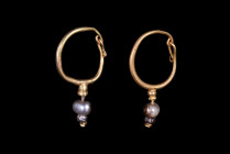 Ca. 100-300 AD.
A charming, matched pair of gold earrings, each of a round hoop tapering to a hook and eye closure. The earrings are embellished with ...