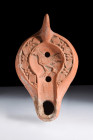 Ca. 450-550 AD.
A moldmade red ware oil lamp, a remarkable example of the Hayes II A type. This lamp boasts a solid lug handle and a recessed tondo, a...