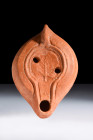 Ca. 350-450 AD.
A redware terracotta oil lamp features a round nozzle and a sculpted lug handle, providing a comfortable grip for the user. The sunken...