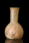 Ca. 200-300 AD.
A unguentarium crafted from yellowish glass with a bulbous lower body and a concave base marked with a pontil scar. The seamless mergi...