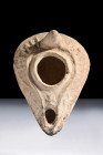 Ca. 600 AD.
A pottery oil lamp with a pear-shaped reservoir draws attention to the central filling aperture, which is thoughtfully encircled by a pron...