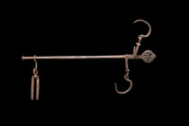 Ca. 100-300 AD.
This steelyard boasts a rod with a pointed finial on one end and an openwork circular decorative terminal on the other. Two hooks dang...
