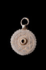 Ca. 200-300 AD.
Crafted from silver, this pendant exhibits a circular and flat form, distinguished by a serrated edge and a suspension loop positioned...